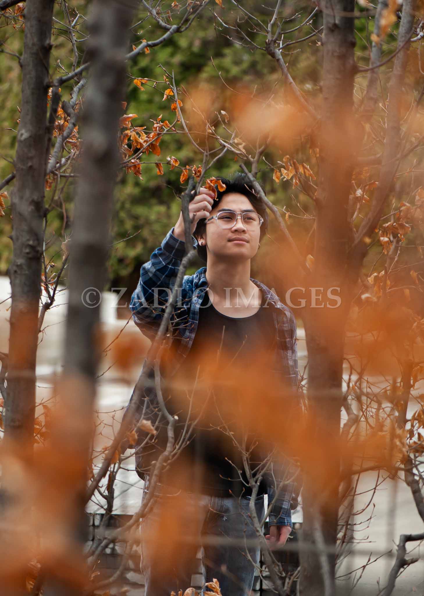 Teen boy between trees.