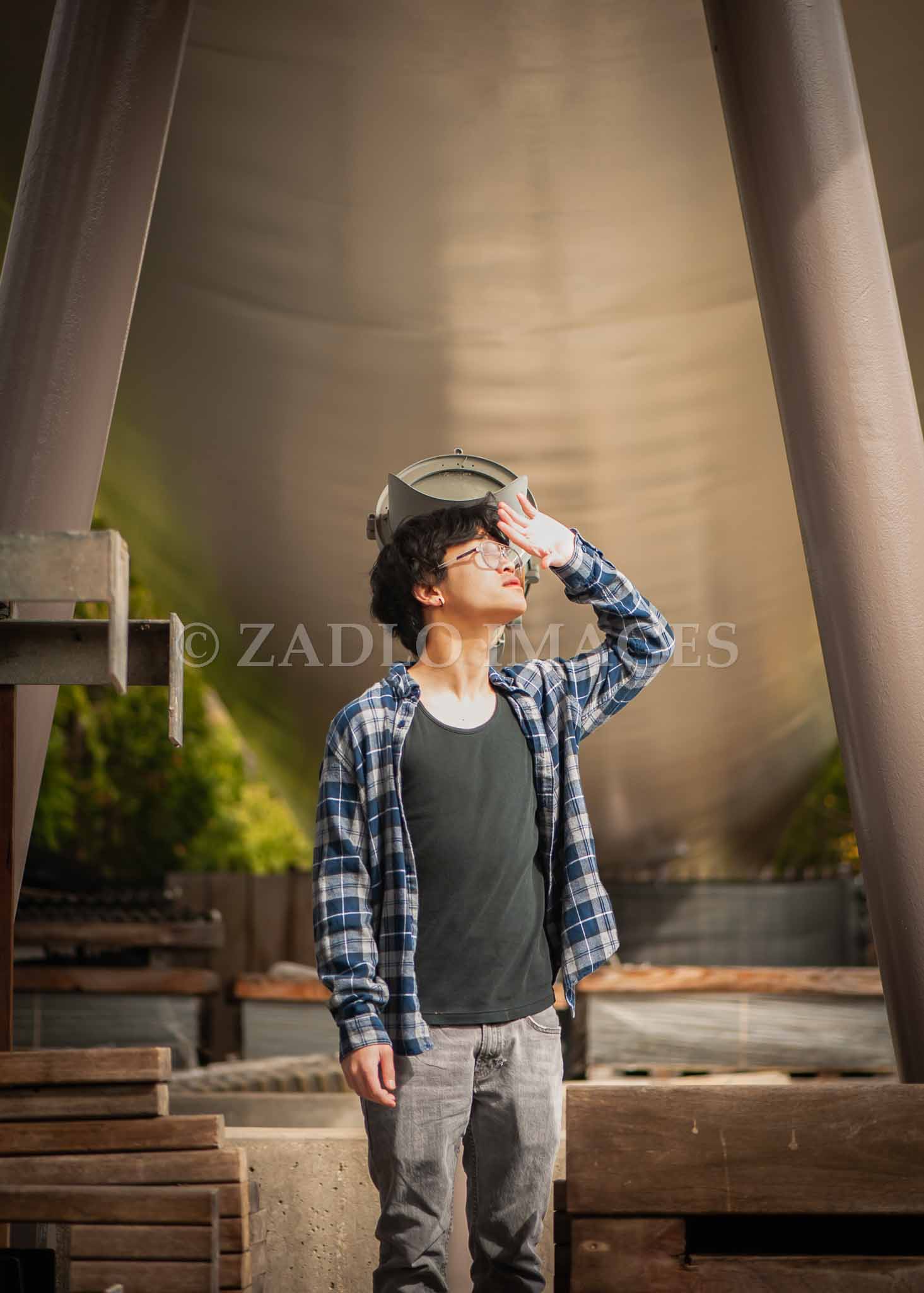 Teen boy standing under bridge looking into the distance.