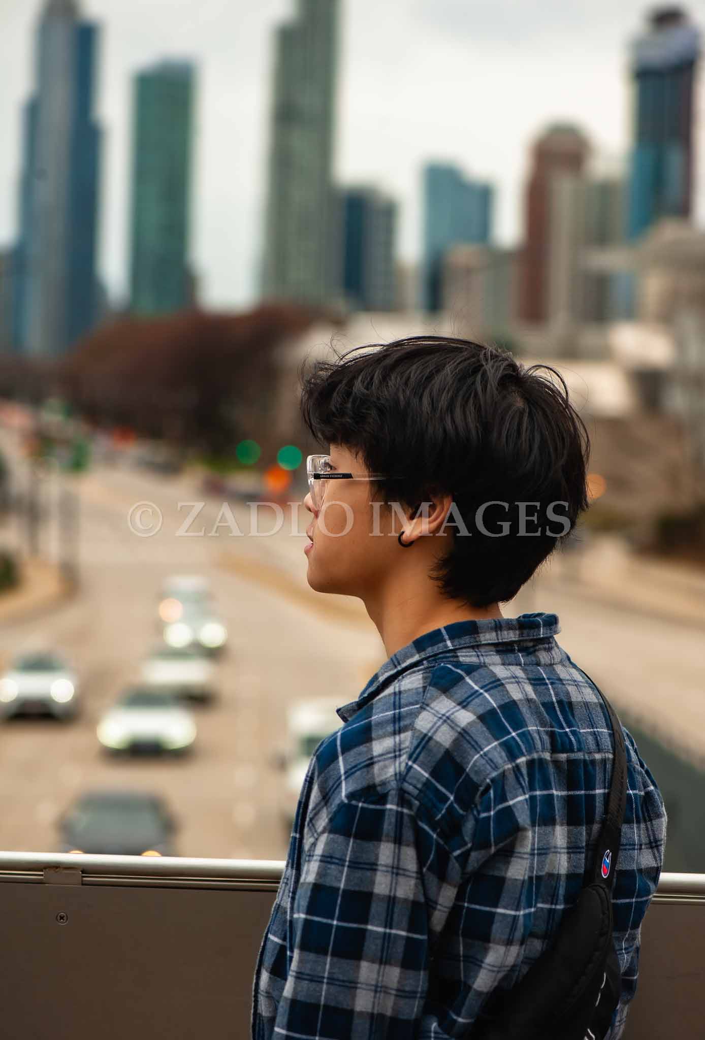 Teen boy looking at cars and skyline.