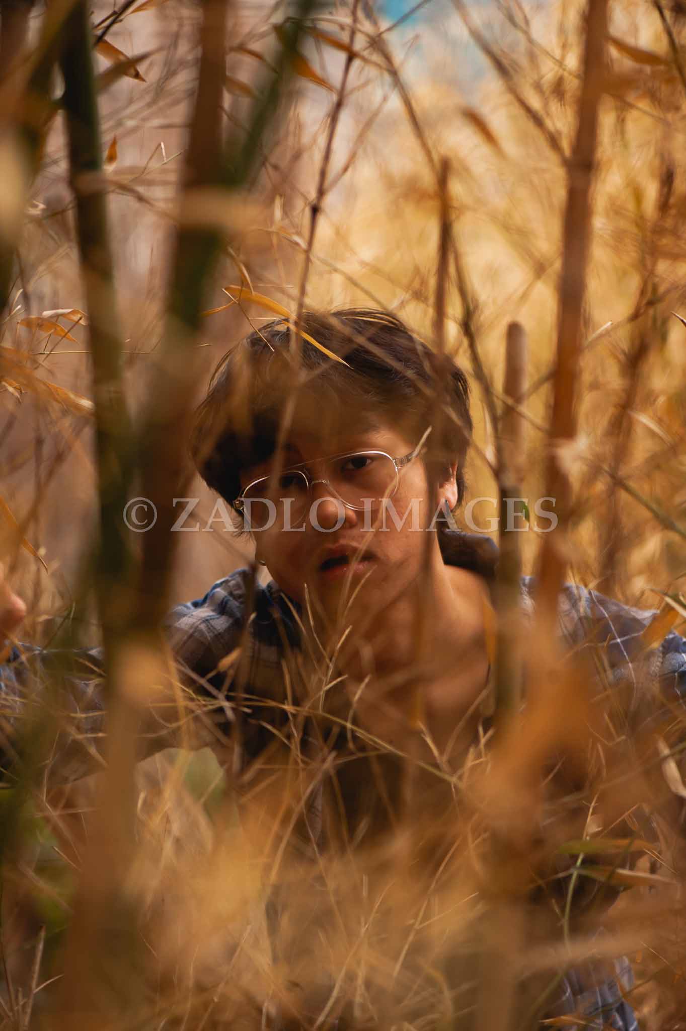 Teen boy looking into the camera through a field.